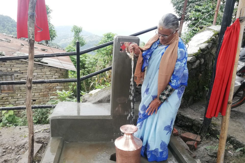 Een vrouw gebruikt het nieuwe watersysteem in Kalika